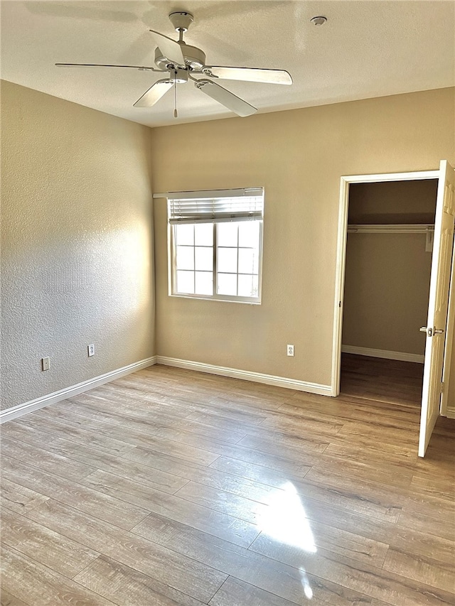 unfurnished bedroom featuring a closet, light wood-type flooring, and ceiling fan