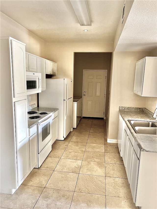 kitchen featuring white cabinets, light tile patterned floors, a textured ceiling, sink, and white appliances