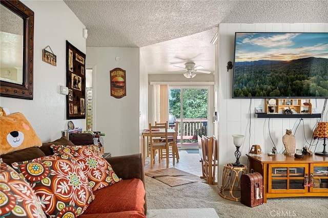 living room featuring ceiling fan, carpet floors, and a textured ceiling