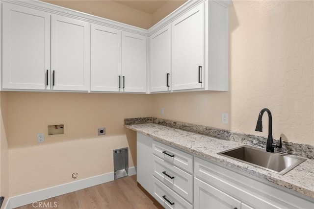 washroom with cabinets, sink, hookup for a washing machine, hookup for an electric dryer, and light hardwood / wood-style floors