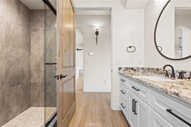 bathroom with hardwood / wood-style flooring, vanity, and tiled shower