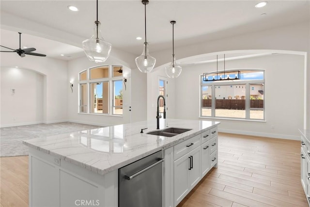 kitchen featuring sink, stainless steel dishwasher, decorative light fixtures, a center island with sink, and white cabinets