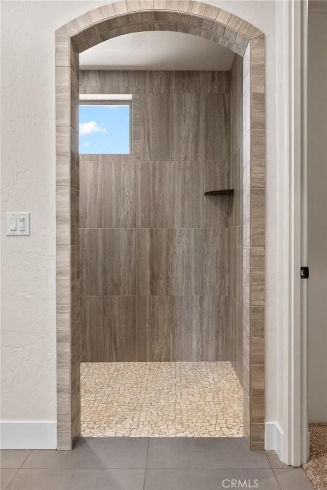 bathroom with tiled shower and tile patterned floors