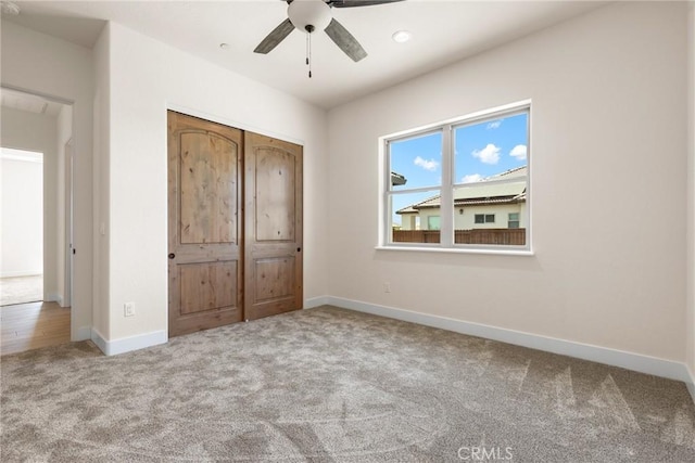 unfurnished bedroom with ceiling fan, light colored carpet, and a closet