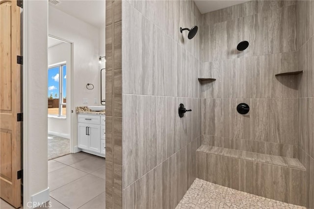 bathroom featuring tile patterned flooring, vanity, and a tile shower