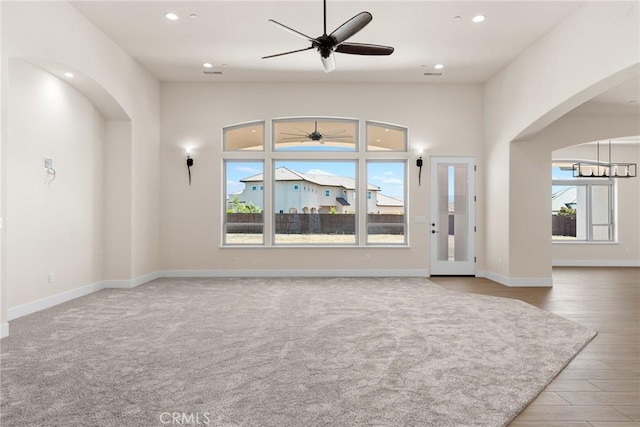 unfurnished living room with ceiling fan with notable chandelier and light colored carpet