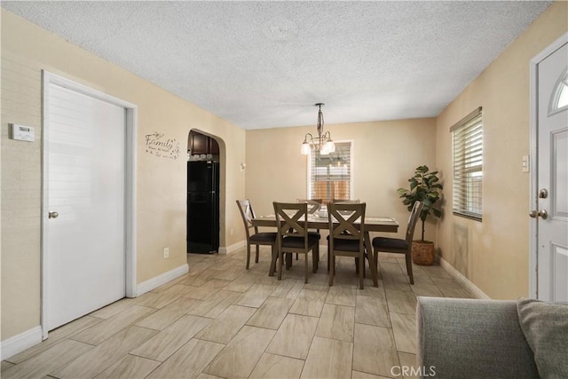 dining room with an inviting chandelier and a textured ceiling