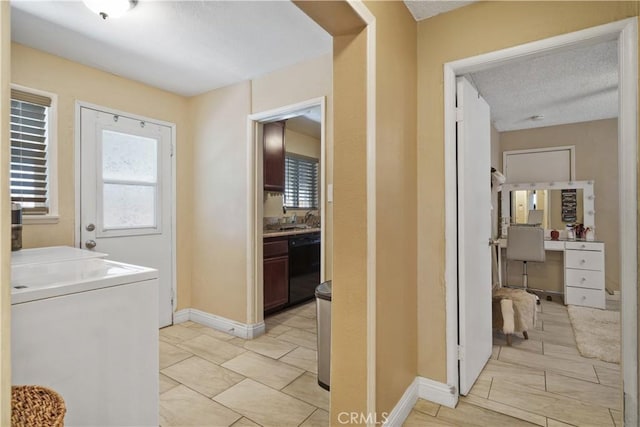 laundry area featuring sink, a textured ceiling, light tile patterned floors, and washer / clothes dryer