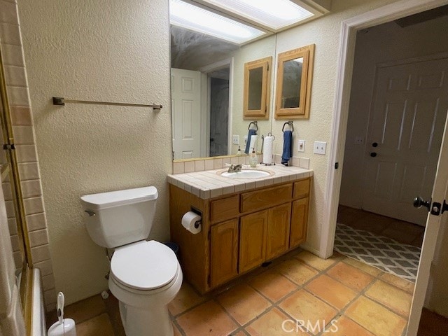 bathroom featuring toilet, vanity, a shower, and tile patterned flooring