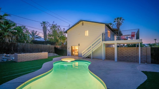 pool at dusk with a patio area, a yard, and an in ground hot tub