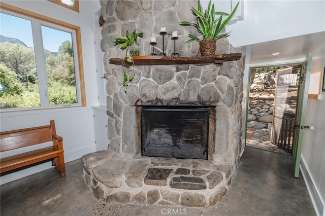 details with a stone fireplace, concrete floors, and a mountain view