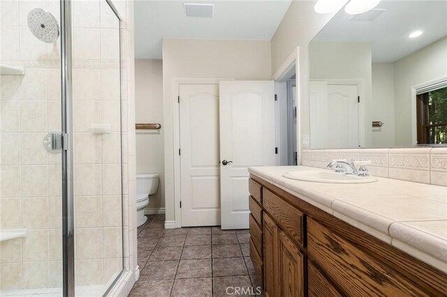 bathroom featuring backsplash, an enclosed shower, toilet, vanity, and tile patterned flooring