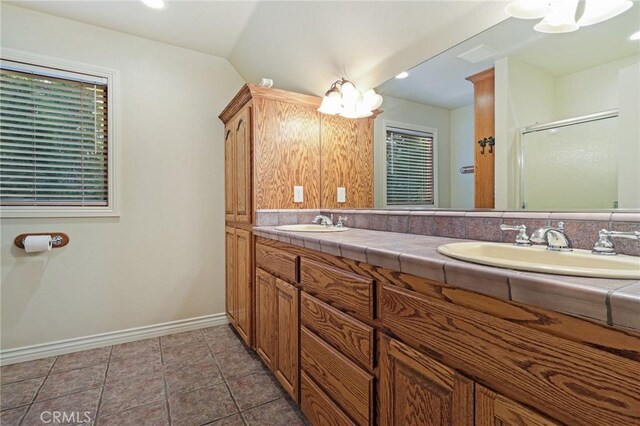 bathroom featuring vanity, walk in shower, lofted ceiling, and tile patterned flooring