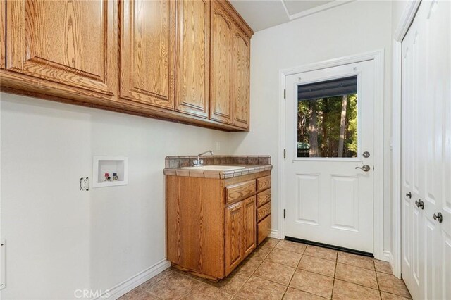 laundry room with sink, washer hookup, light tile patterned floors, and cabinets