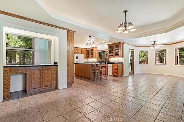 kitchen featuring white appliances, brown cabinetry, dark countertops, and glass insert cabinets