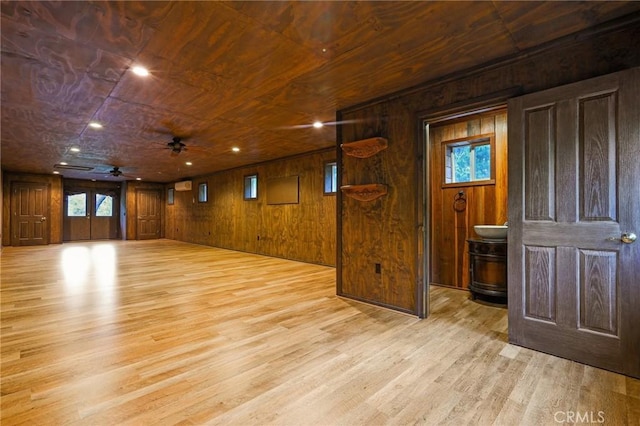 empty room with wooden ceiling, light wood-style flooring, wooden walls, and a ceiling fan