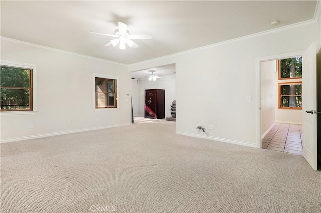 empty room featuring crown molding, baseboards, a ceiling fan, and light colored carpet