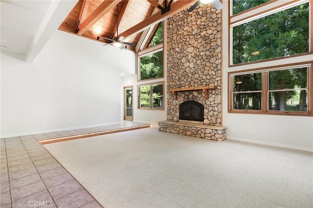 unfurnished living room featuring light tile patterned floors, a ceiling fan, a stone fireplace, high vaulted ceiling, and beam ceiling