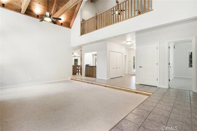 unfurnished living room with carpet flooring, wood ceiling, ceiling fan, beamed ceiling, and high vaulted ceiling