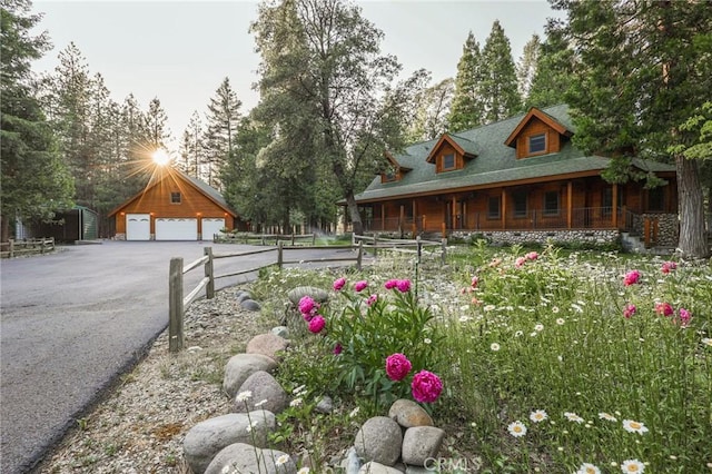 view of yard featuring a garage, covered porch, driveway, and an outdoor structure