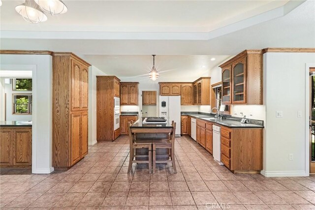 kitchen featuring sink, a center island, a breakfast bar, light tile patterned floors, and white appliances