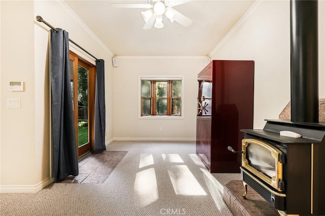 foyer entrance with a wood stove, baseboards, ornamental molding, and a ceiling fan