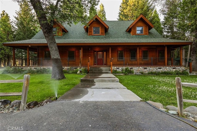 view of front facade with a porch, a front yard, and a shingled roof