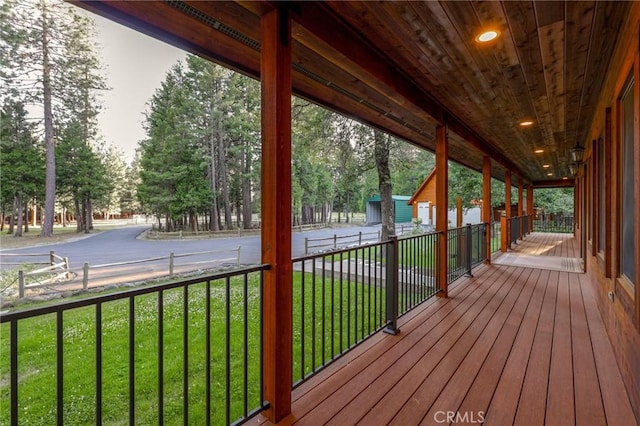 wooden terrace featuring a porch and a yard