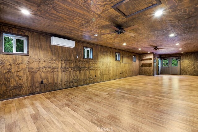 interior space with wood walls, a wealth of natural light, and light wood-type flooring