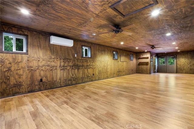 below grade area featuring ceiling fan, a wall unit AC, recessed lighting, wooden walls, and light wood finished floors