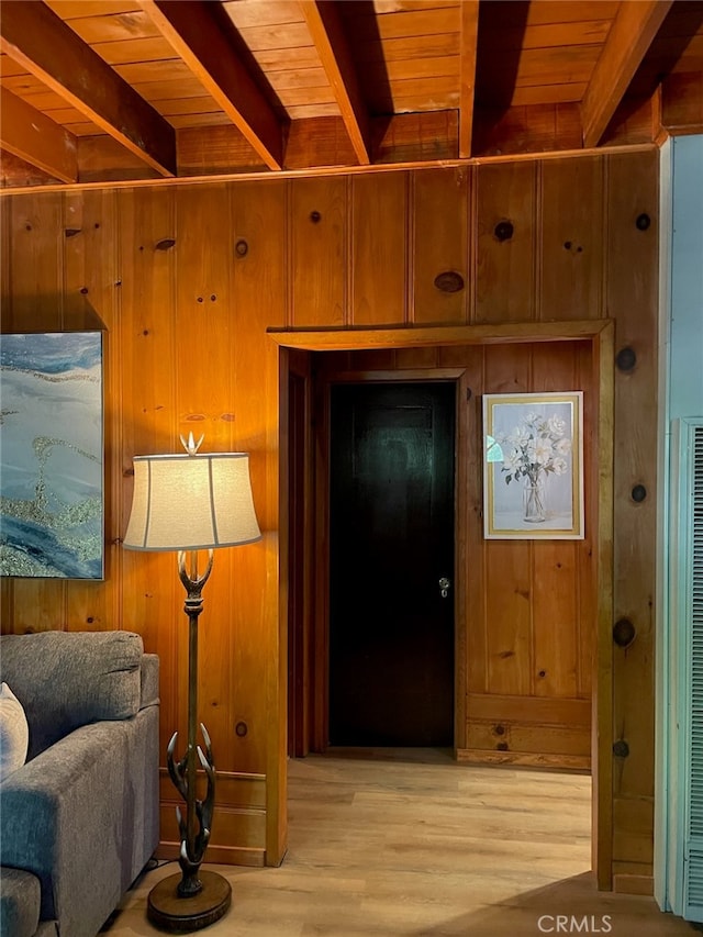 living area featuring light hardwood / wood-style flooring, beam ceiling, wooden walls, and wooden ceiling