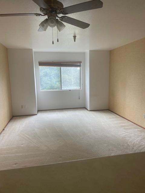 unfurnished room featuring ceiling fan and light carpet