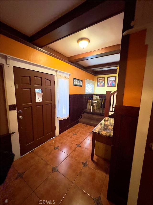 entryway featuring beamed ceiling, tile patterned floors, and wooden walls