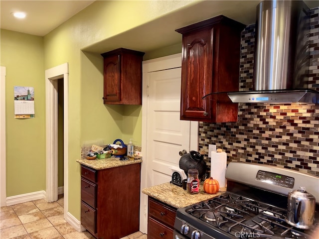 kitchen with decorative backsplash, light stone countertops, wall chimney range hood, and stainless steel range with gas stovetop