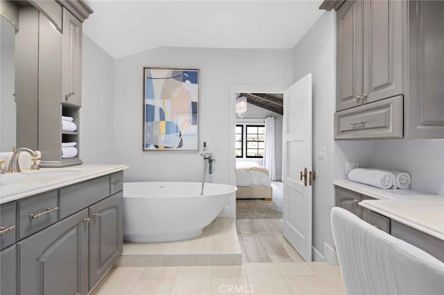 bathroom featuring vaulted ceiling, tile patterned flooring, a bathtub, and vanity