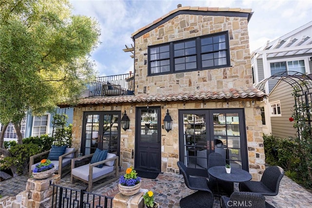 rear view of house featuring a patio area, french doors, and a balcony