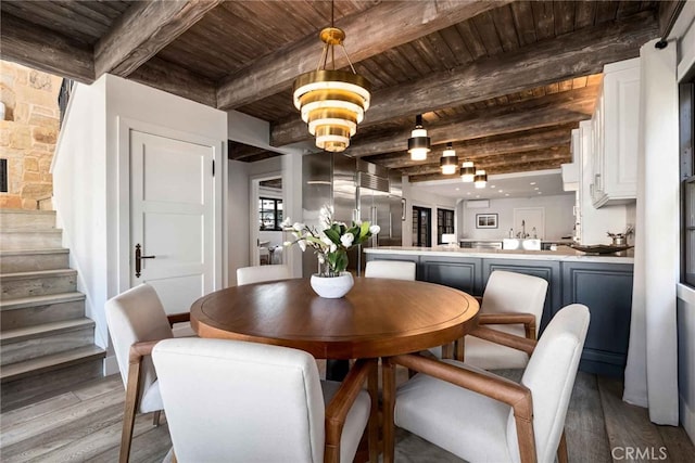 dining room featuring wood ceiling, wood-type flooring, a notable chandelier, and beamed ceiling