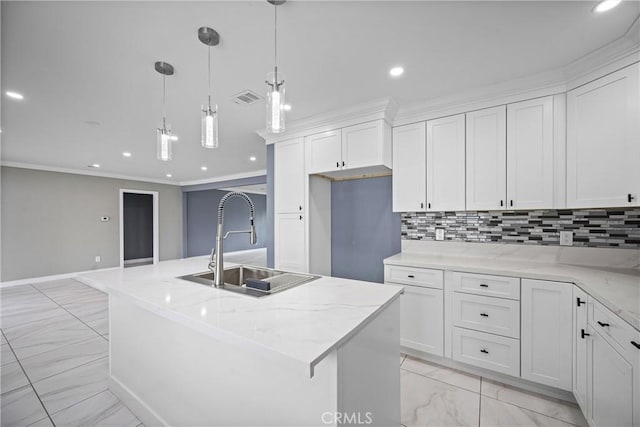 kitchen featuring backsplash, pendant lighting, white cabinetry, and an island with sink