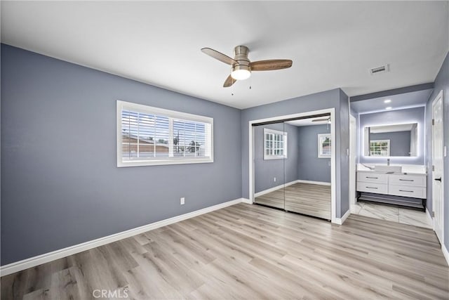 unfurnished bedroom with ceiling fan, a closet, light wood-type flooring, and multiple windows