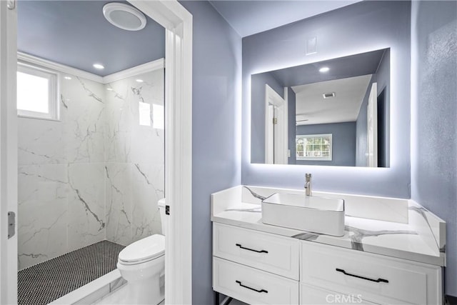 bathroom featuring vanity, toilet, and a tile shower