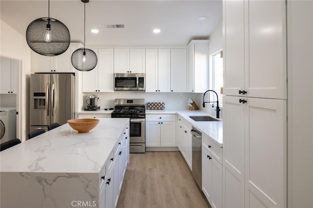 kitchen featuring decorative light fixtures, a center island, sink, appliances with stainless steel finishes, and white cabinets