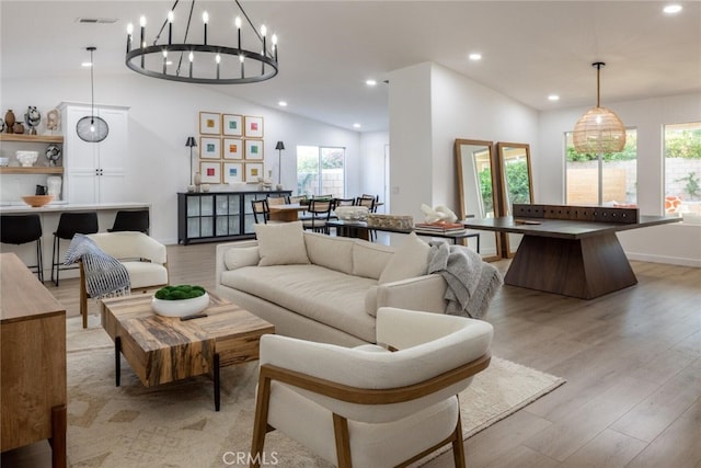 living room featuring light hardwood / wood-style floors, lofted ceiling, and a notable chandelier