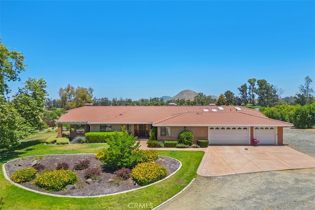 ranch-style home with a mountain view, a front lawn, and a garage