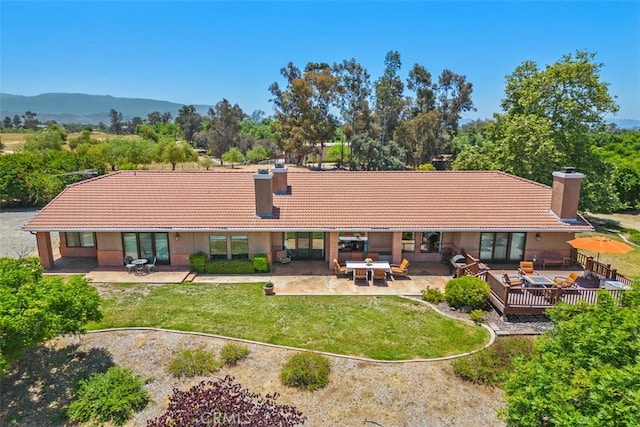 back of house with a yard, a patio area, a deck with mountain view, and outdoor lounge area