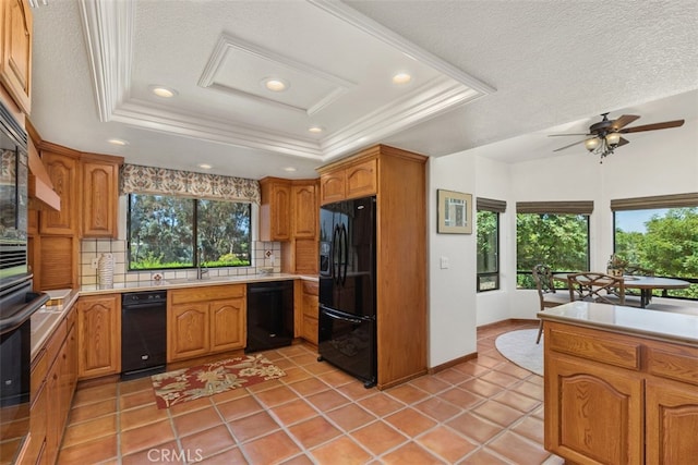 kitchen with decorative backsplash, black appliances, a tray ceiling, and a wealth of natural light