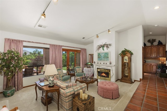 living room with rail lighting, a premium fireplace, lofted ceiling, and light tile patterned floors