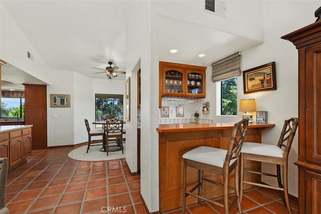 bar with ceiling fan, tile countertops, and dark tile patterned floors