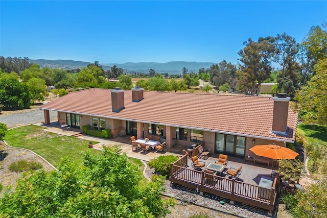 rear view of property featuring an outdoor hangout area, a patio, and a deck with mountain view