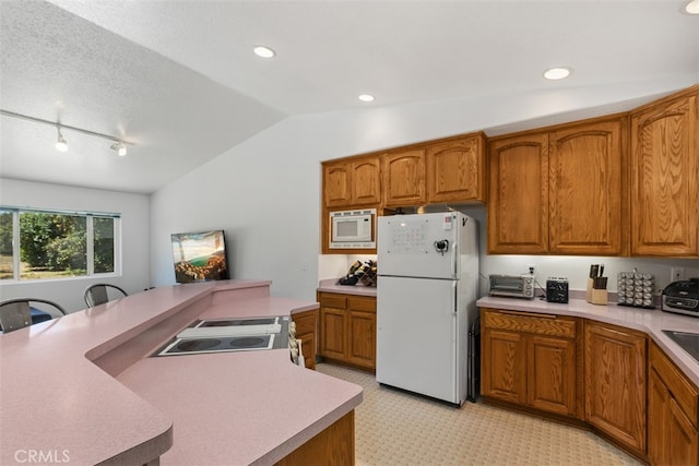 kitchen with white appliances, a textured ceiling, track lighting, and vaulted ceiling