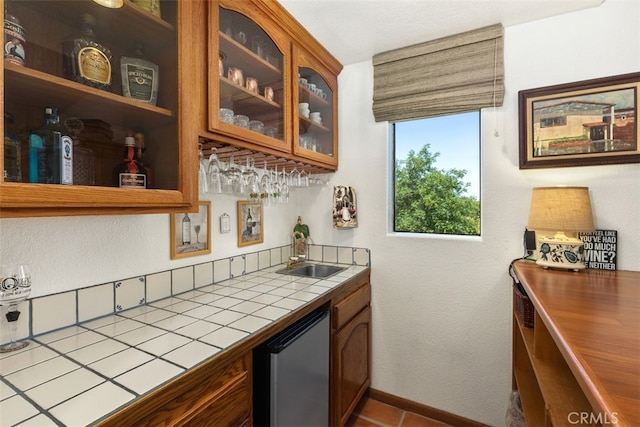 bar featuring stainless steel dishwasher, tile counters, sink, and tile patterned flooring